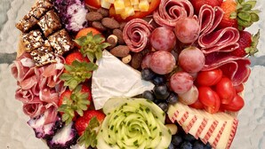 Un plateau de fruits et de fromages comprenant divers éléments, notamment des raisins, des fraises et différents types de fromage.