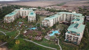 A resort with multiple buildings, a central pool, and surrounding greenery.