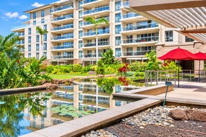 A hotel with a swimming pool, lush greenery, and a multi-story building with balconies.