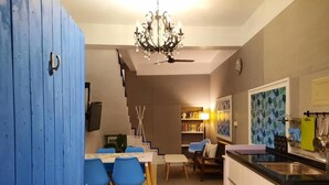 A modern kitchen with a dining area, a chandelier, and a staircase leading to another level. - Lunasea Apartment (Hengchun)
