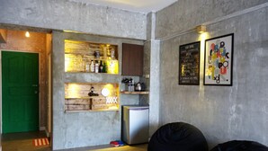 A compact living space with a kitchenette, a green door, and a wall-mounted shelf with bottles. - Lunasea Apartment (Hengchun)
