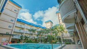 A hotel with a swimming pool surrounded by palm trees and a clear blue sky. - Lunasea Apartment (Hengchun)