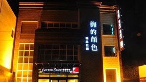 A building with a coffee shop sign and a large illuminated sign on the side. - The Colors Under The Sea (Hengchun)