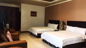 Quarto de hotel com duas camas, um sofá, uma mesa pequena e um quadro na parede.