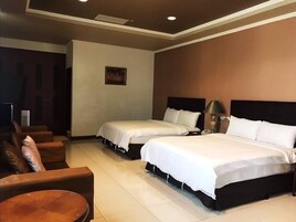 A hotel room with two beds, a sofa, a small table, and a painting on the wall.