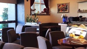 A cozy restaurant with cushioned seating, a coffee shop sign, a window with curtains, and a decorative painting. - The Colors Under The Sea (Hengchun)