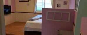 A room with a bed, a television, and a window with curtains.