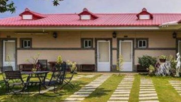 A two-story building with a red roof, a covered patio with a table and chairs, and a small garden area. - Landscape Rural B&B (Checheng)