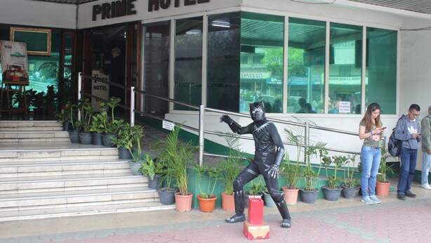 The exterior of the Prime Hotel with a staircase leading up to the entrance, potted plants lining the steps, and a person in a black costume standing on the steps. - Benguet Prime Hotel (Baguio)