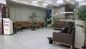 A hotel lobby with a reception desk, two sofas, a staircase, and potted plants. - Benguet Prime Hotel (Baguio)