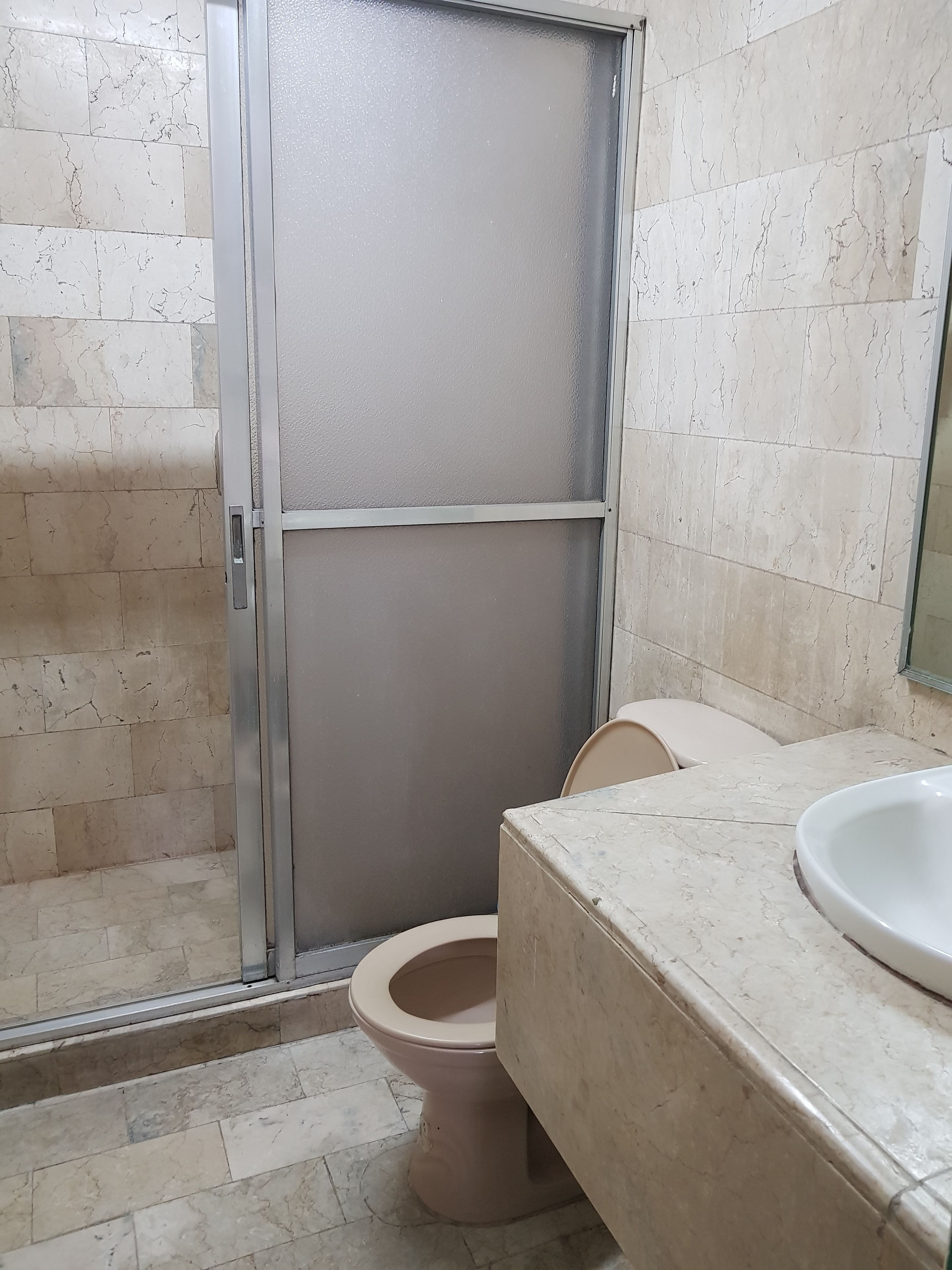 Un baño con inodoro, cabina de ducha y lavabo.