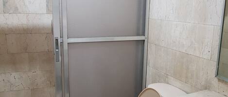 Un baño con inodoro, cabina de ducha y lavabo.