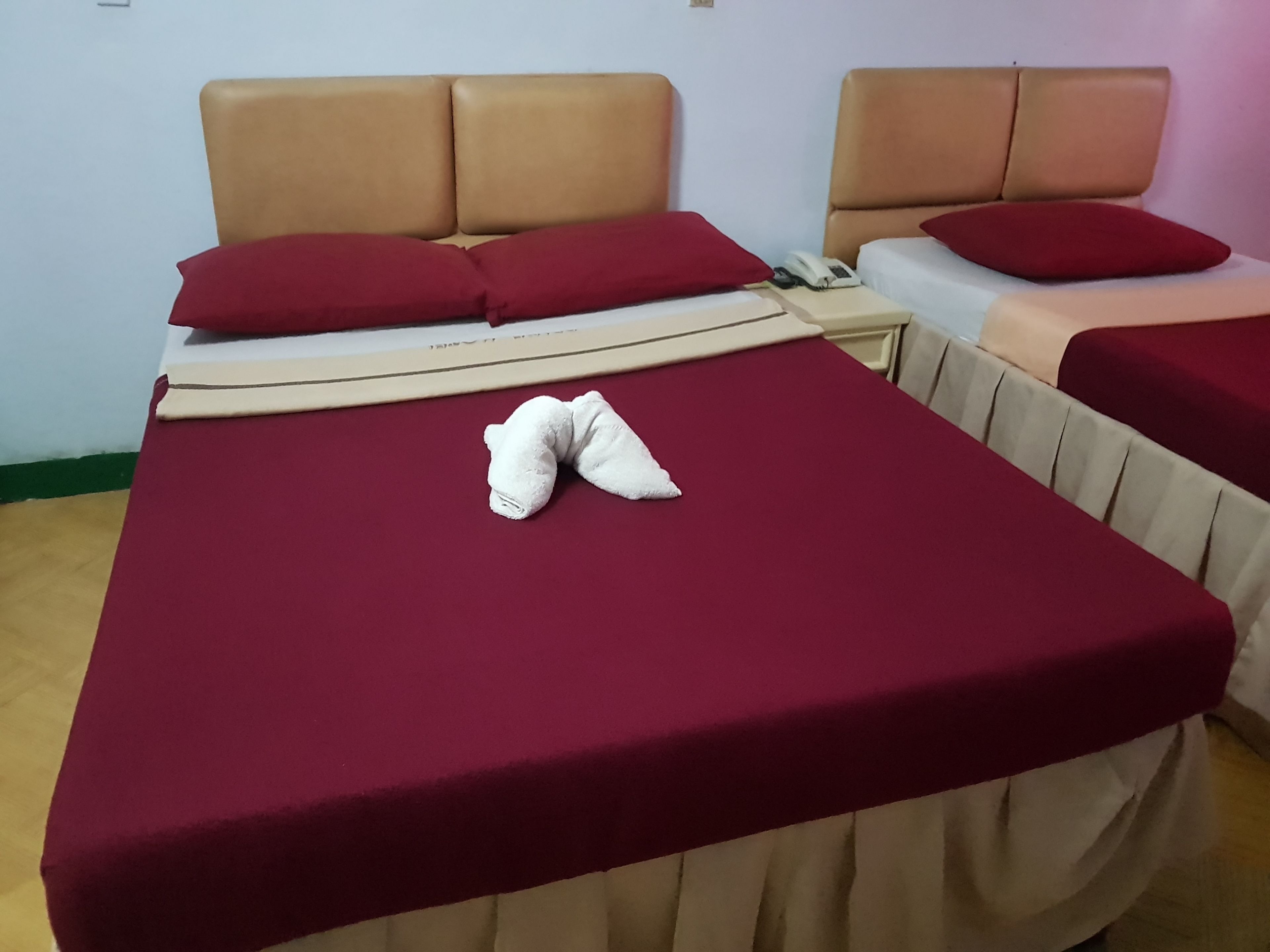Una habitación de hotel con una cama grande, dos mesitas de noche y una manta roja.