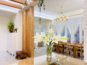 Un comedor con una mesa, sillas y plantas colgantes.