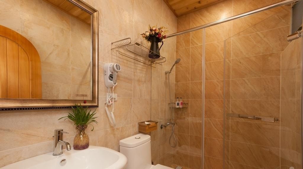 A bathroom with a sink, mirror, hairdryer, and shower.