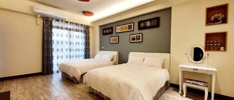 Habitación de hotel con dos camas, un tocador con espejo y un plafón con lámpara en forma de fruta.