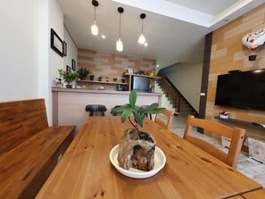 Un espace repas comprenant une table en bois, des chaises et une plante placée au centre.