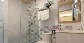 Une salle de bain avec une douche à parois de verre, des toilettes et un coin lavabo avec un miroir et des articles de toilette.