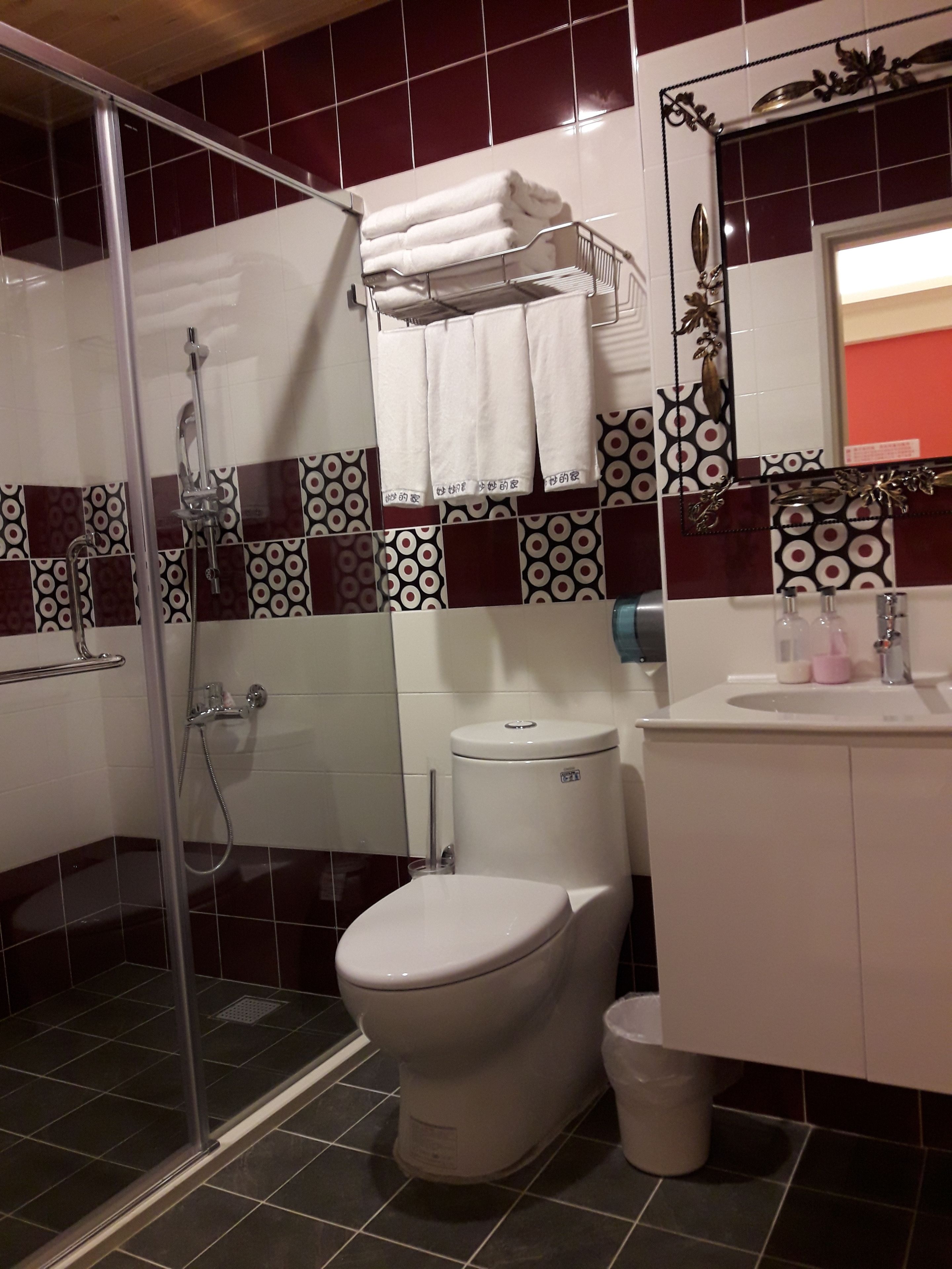 A bathroom with a glass-enclosed shower, a toilet, and a sink with toiletries.