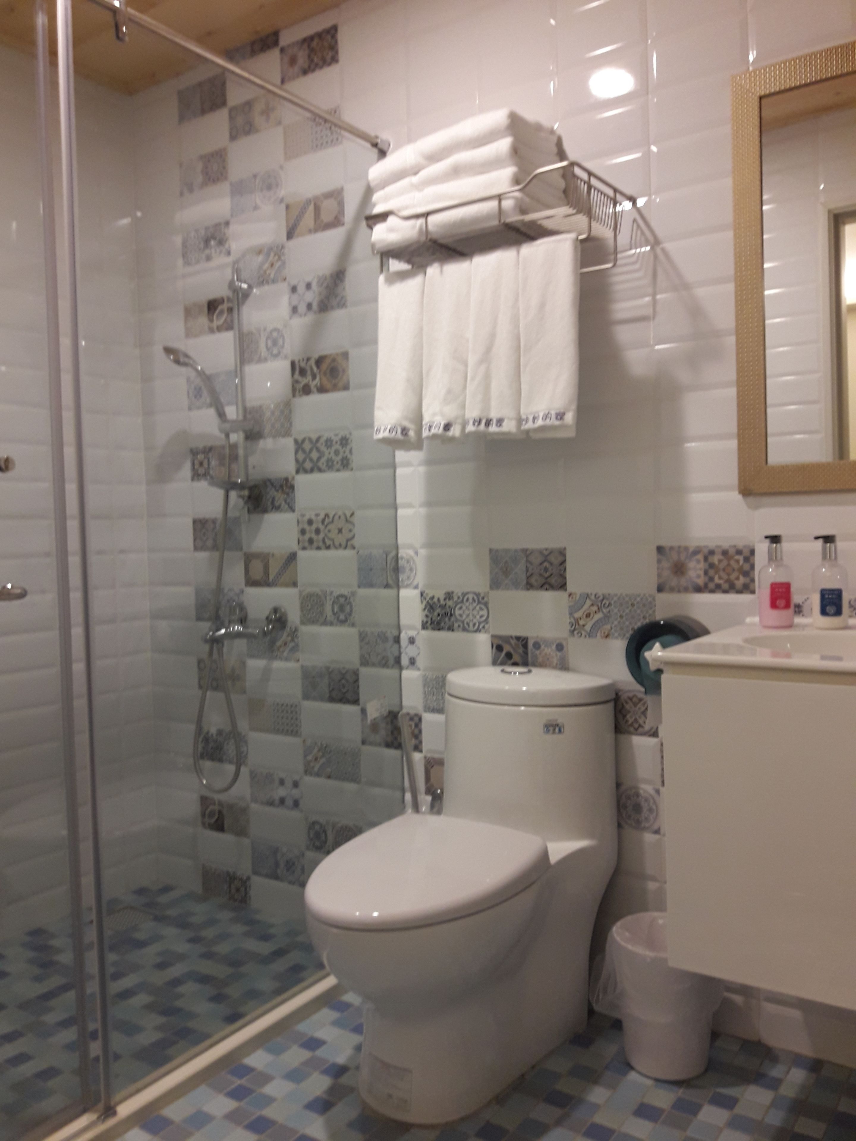 A bathroom with a glass-enclosed shower, a toilet, and a sink with a mirror above it.