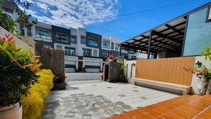 A modern outdoor area with a tiled patio, potted plants, and a wooden bench. - Miao Miao de jia (Taitung)