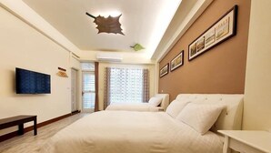 A hotel room with a large bed, a flat-screen TV mounted on the wall, a bench, and a ceiling light fixture. - Miao Miao de jia (Taitung)
