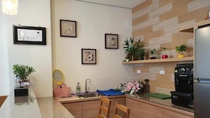 A modern kitchen with wooden cabinets, a built-in coffee machine, and a sink. There are framed pictures on the wall and potted plants on the shelves. - Miao Miao de jia (Taitung)