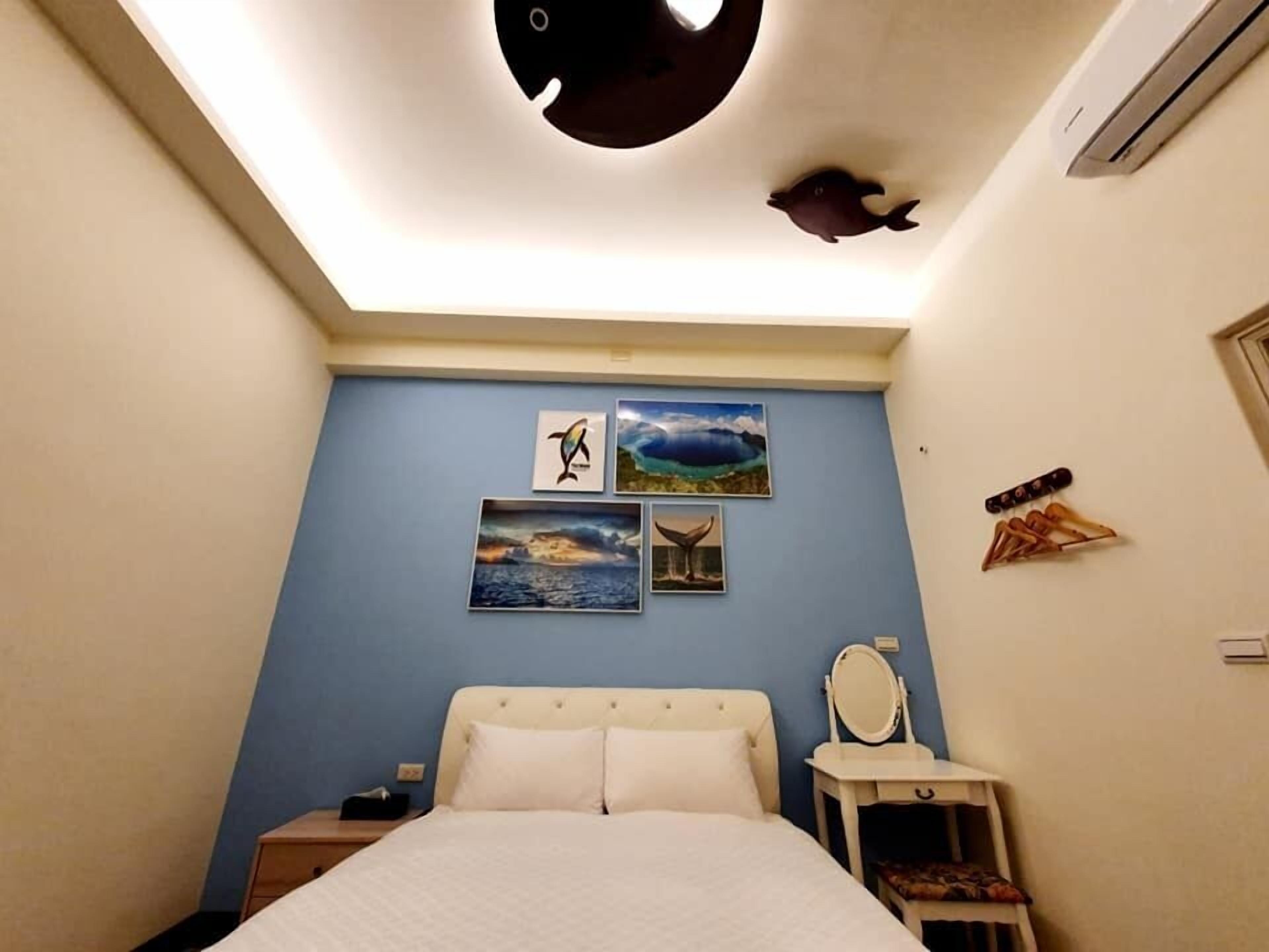Un dormitorio con cama, mesita de noche, cómoda y decoración en la pared.