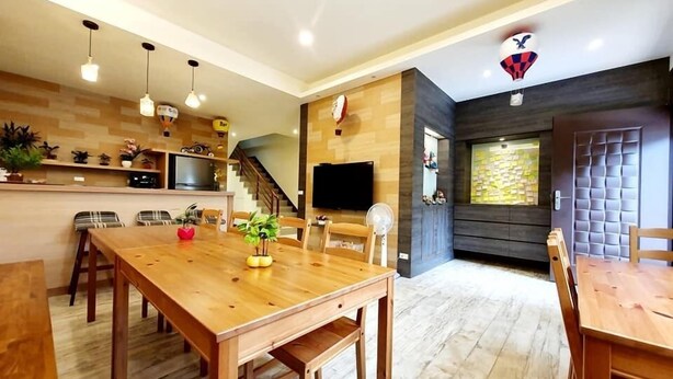 A modern kitchen with wooden cabinets, a dining area with a wooden table, and a staircase leading to another level. - Miao Miao de jia (Taitung)