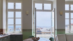 A dining area with a view of the sea, large windows, and a table with a bowl. - Guesthouse Lila (Syros)