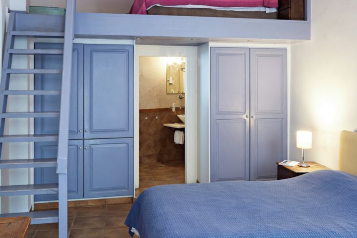 A bedroom with a bunk bed, a staircase, and a bathroom visible through an open door.
