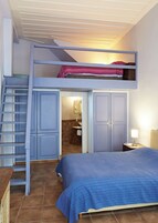 Un dormitorio con literas, un armario, una mesita de noche y una lámpara.