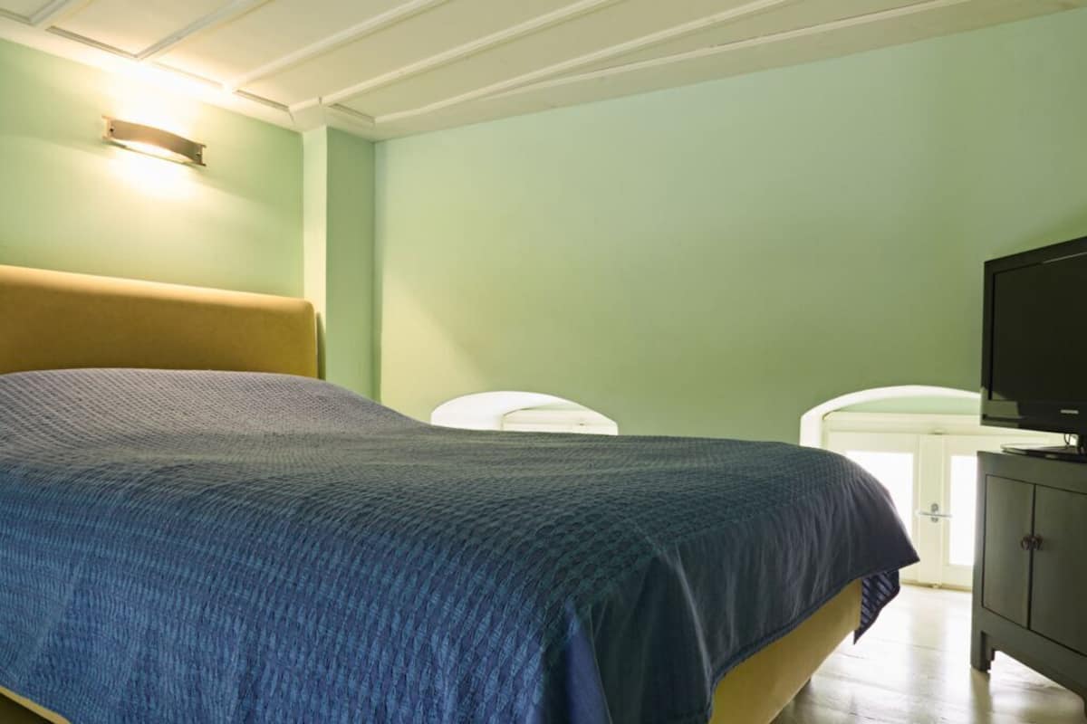 Quarto com cama, televisão e armário.