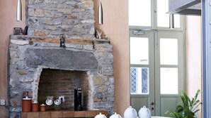 A stone fireplace with a shelf above it holding decorative items. - Guesthouse Lila (Syros)