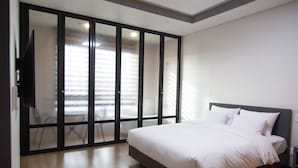 A bedroom with a large bed, a sliding glass door, and a flat-screen TV.