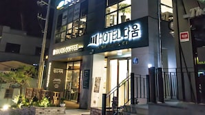 A hotel with a sign reading "HOTEL DAEUM" and "HAND'S COFFEE" below it. There are steps leading up to the entrance, and the building has multiple floors.