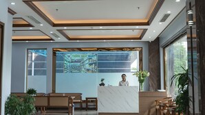 A hotel reception area with a marble reception desk, wooden benches, and a chandelier. - Hello Hotel (Vo Cuong)