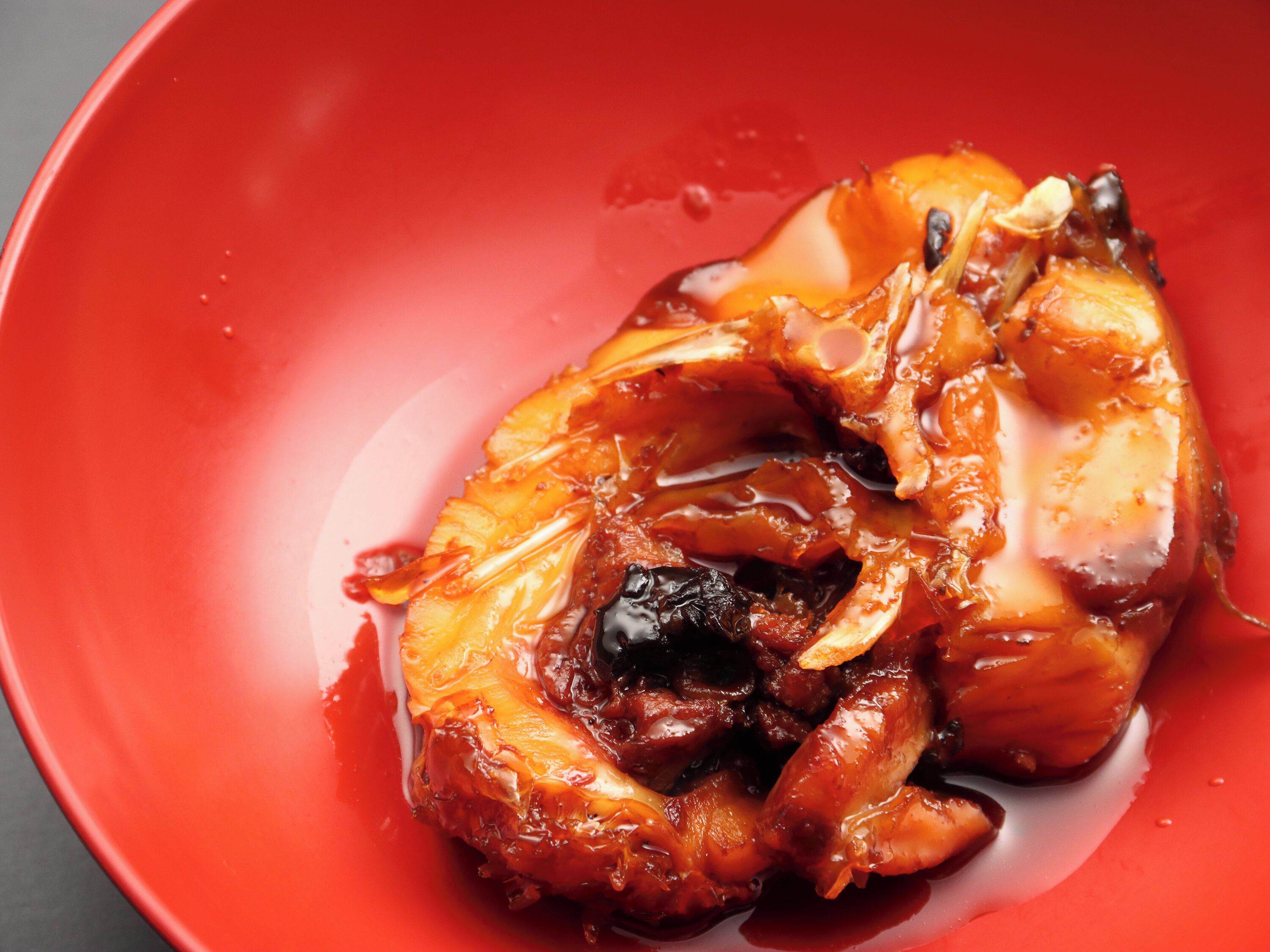 A red plate with a glazed chicken dish.