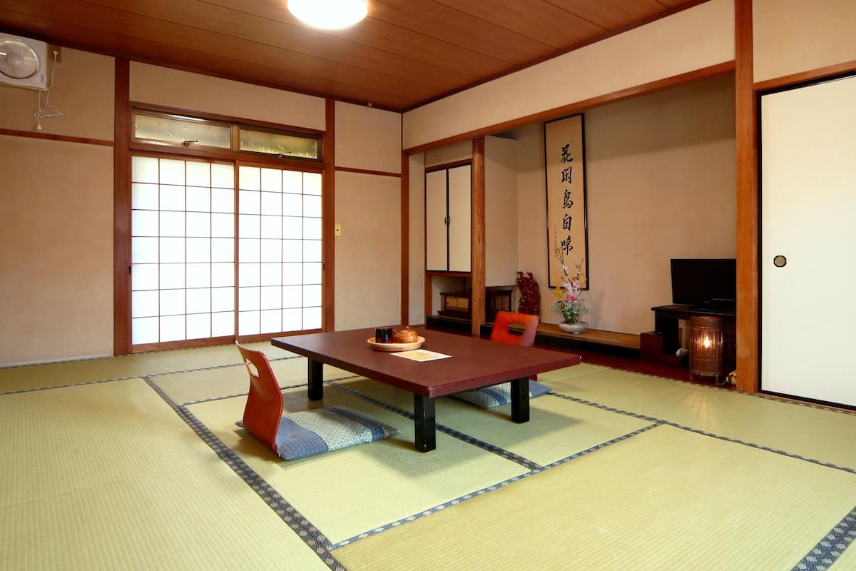 A traditional Japanese room with tatami flooring, a low table, and sliding doors.
