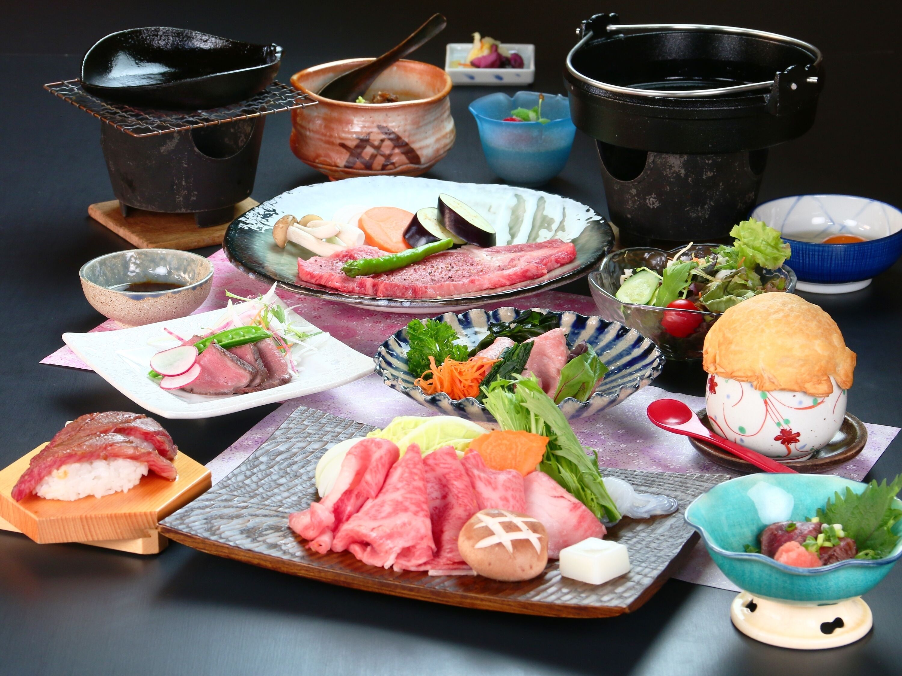 A variety of dishes including sushi, sashimi, and vegetables, arranged on a table with multiple bowls and plates.