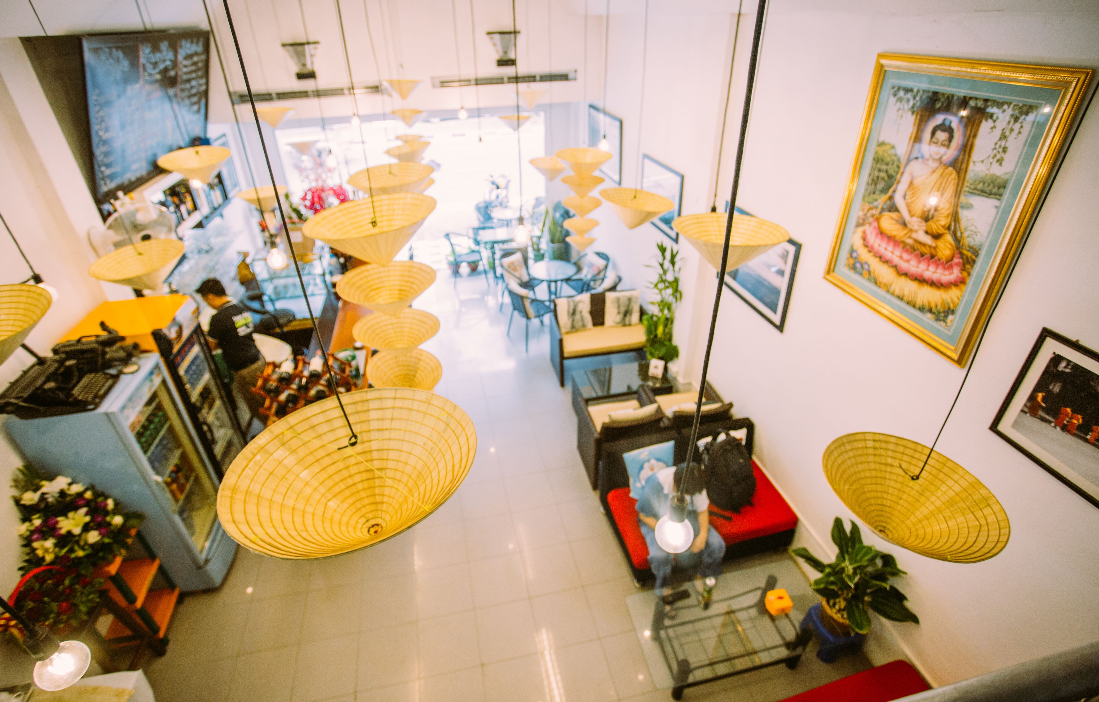 Un hall d’entrée spacieux, doté de plusieurs coins salon, de lampes suspendues et d’une statue de Bouddha.