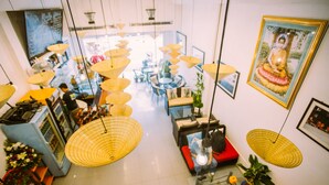 A spacious lobby with multiple seating areas, hanging lamps, and a Buddha statue. - Green Box Hotel - Hostel (Vientiane)