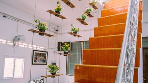 A staircase with wooden steps and metal railings, flanked by hanging planters with flowers. - Green Box Hotel - Hostel (Vientiane)