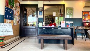 A reception desk with a person seated behind it, surrounded by various informational posters and a map on the wall. - Madpackers Delhi - Hostel (New Delhi)