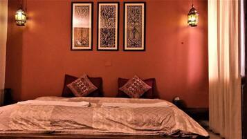 A bedroom with a bed, two pillows, a nightstand, and three wall-mounted decorative items.