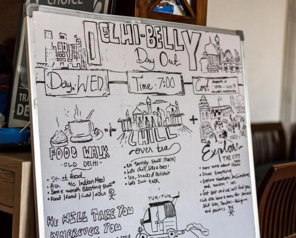 A whiteboard with hand-drawn sketches and text describing a day out in Delhi, including food, chill, and exploration.