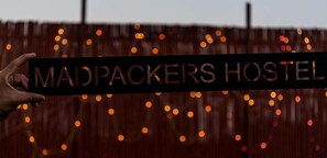 A sign for 'MADPACKERS HOSTEL' with a hand holding it. - Madpackers Delhi - Hostel (New Delhi)