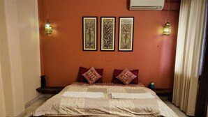 A bedroom with a large bed, patterned pillows, and wall-mounted artwork. - Madpackers Delhi - Hostel (New Delhi)