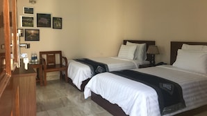 Une chambre d’hôtel avec deux lits, un bureau, une chaise et un climatiseur fixé au mur.