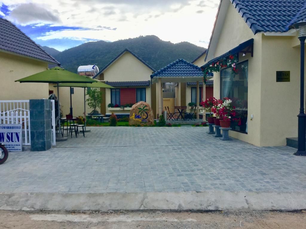 A hotel entrance with a paved driveway, outdoor seating, and a mountain backdrop.